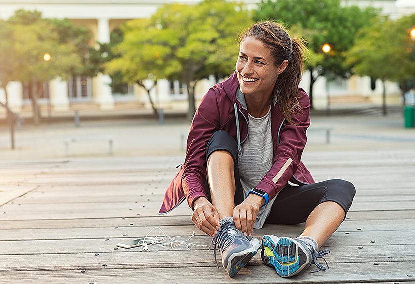 Woman tying running shoes before jogging on a trail.